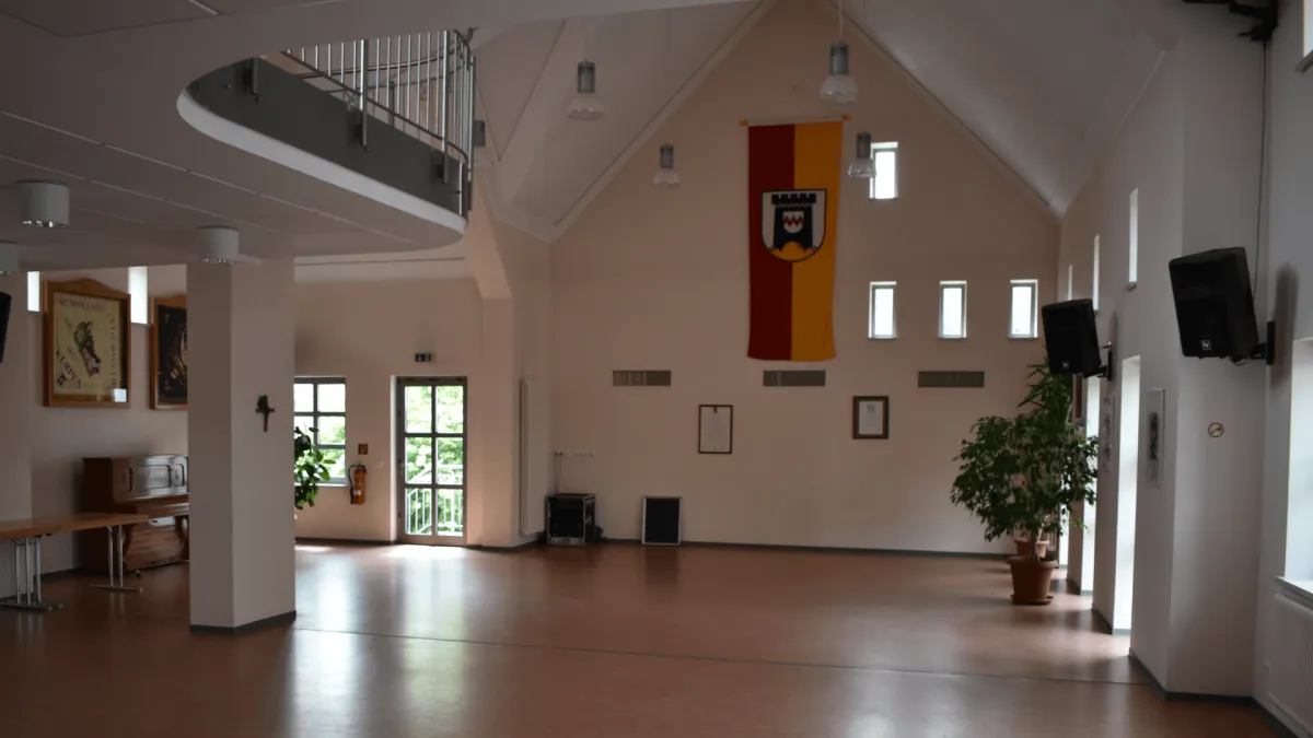 Saal im Gemeindehaus Kerpen mit Wappenbanner und Empore