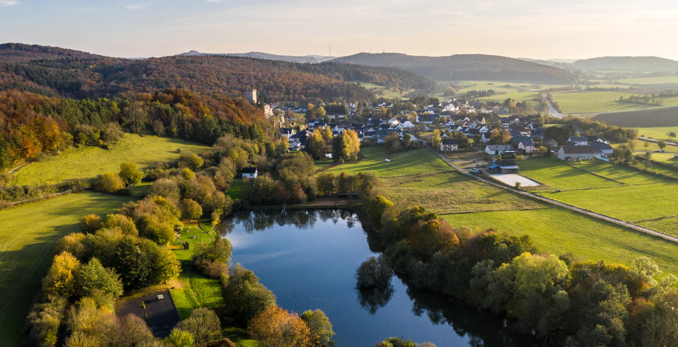 Ruderbach-Stausee bei Kerpen mit Ortschaft und Eifellandschaft im Herbst