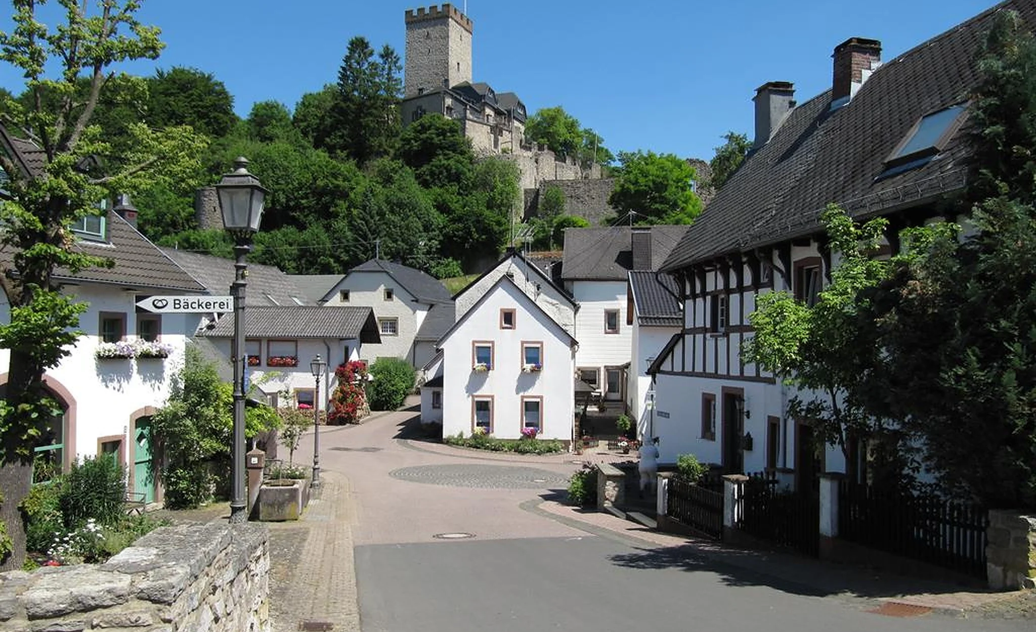 Historische Dorfstraße in Kerpen mit Fachwerkhäusern und Burg im Hintergrund