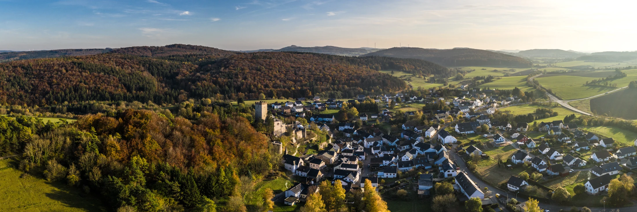 Panoramablick über Kerpen in der Eifel mit Burgturm, Dorf und herbstlich gefärbten Wäldern